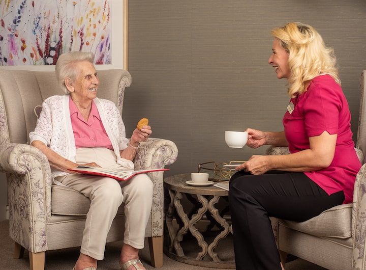 Happy care home resident with caring member of staff drinking tea